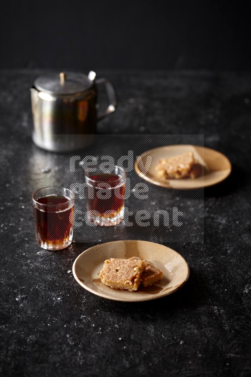 Basbousa with tea in a dark setup