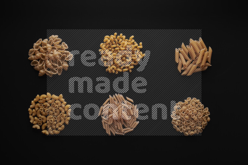 Different pasta types in bunches on black background