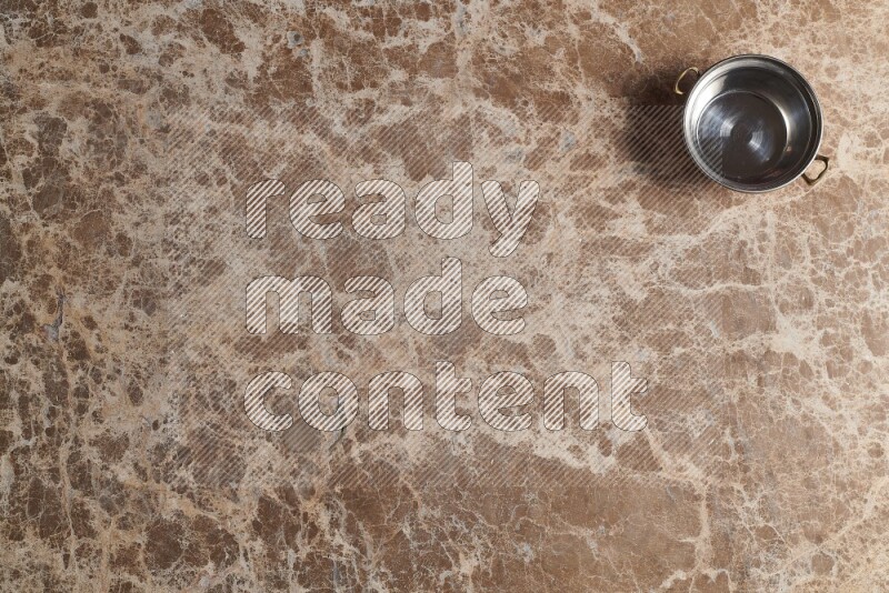 A small copper pot on beige marble background
