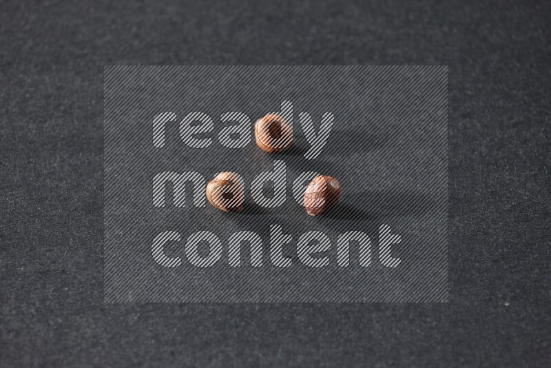 3 peeled hazelnuts on a black background in different angles