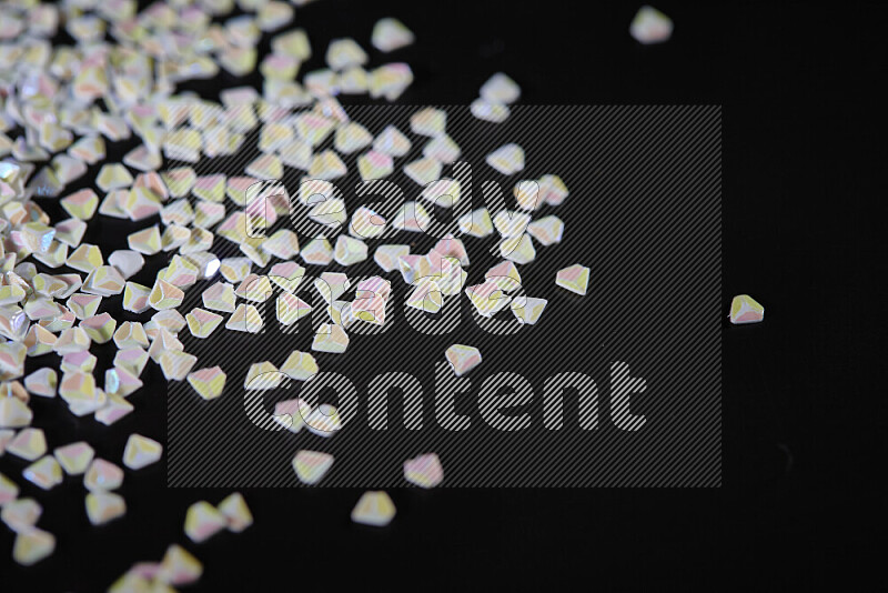 Colorful plastic shards for decoration scattered on a black background