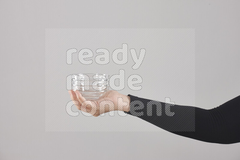 A woman in black abaya holding different glassware in different positions