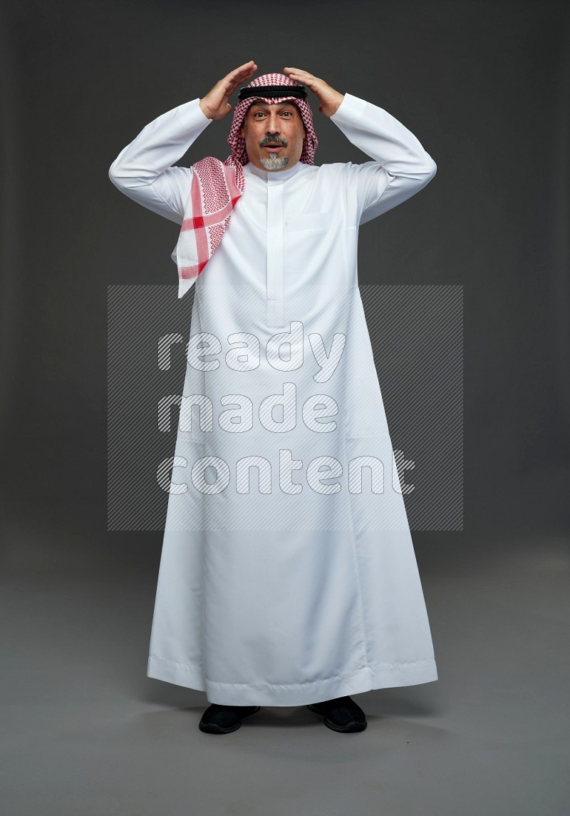 Saudi man with shomag Standing Interacting with the camera on gray background