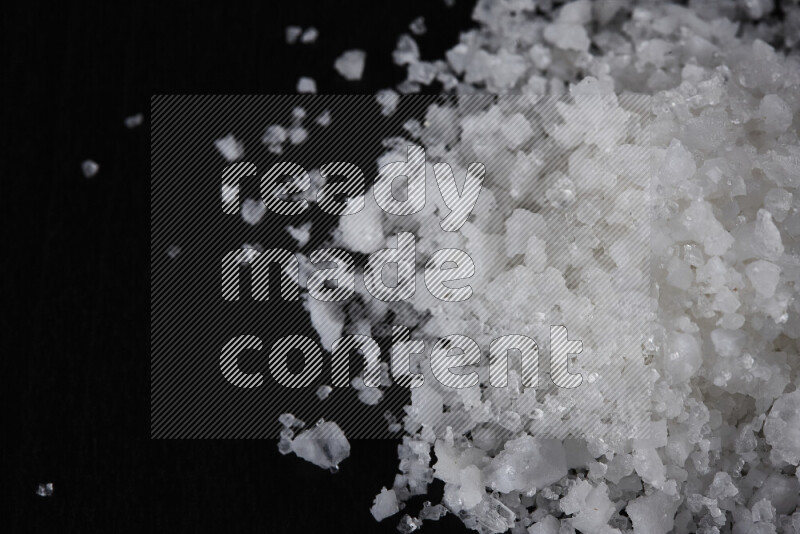 A bunch of coarse sea salt crystals on black background