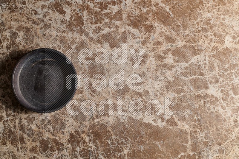 Top View Shot Of A Black Pottery Oven Plate On beige Marble Flooring