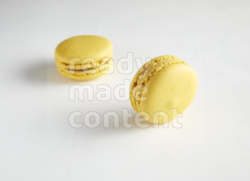 45º Shot of two Yellow Lemon macarons on white background