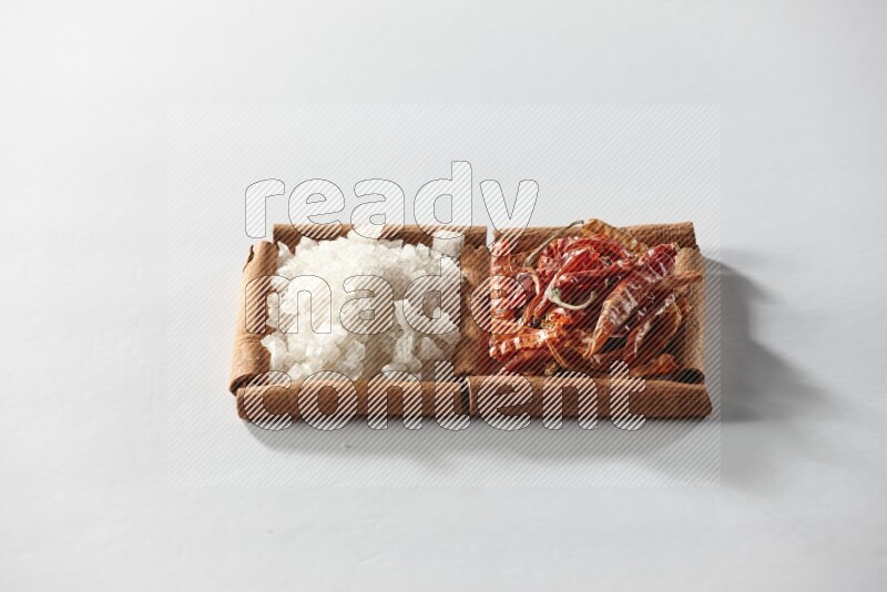 مربعان من أعواد القرفة ممتلئان بالفلفل الحار المجفف والملح الأبيض علي خلفية بيضاء