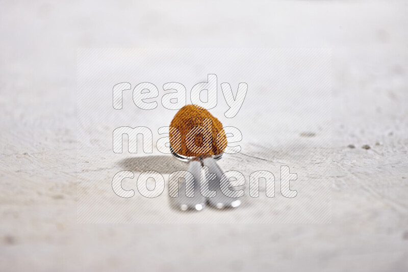 Two metal spoons full of ground paprika powder on white background