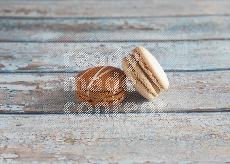 45º Shot of of two assorted Brown Irish Cream, and White Caramel fleur de sel macarons on light blue background