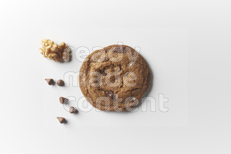 A single chocolate chips cookie with chocolate and walnuts beside it on a white background