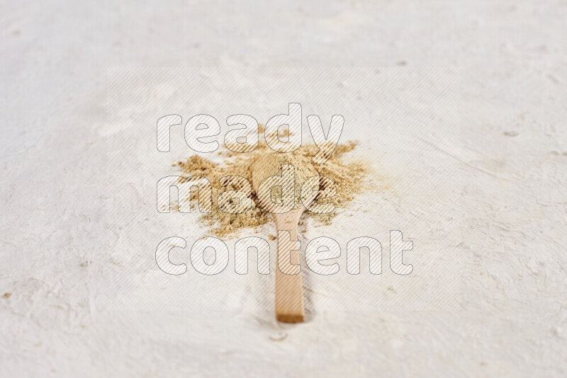 A wooden spoon full of ground ginger powder on white background