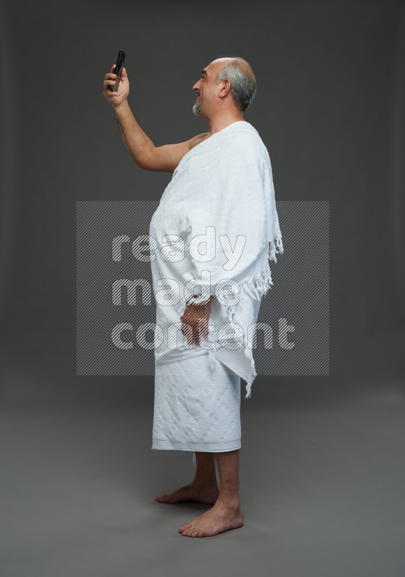 A man wearing Ehram Standing taking selfie on gray background