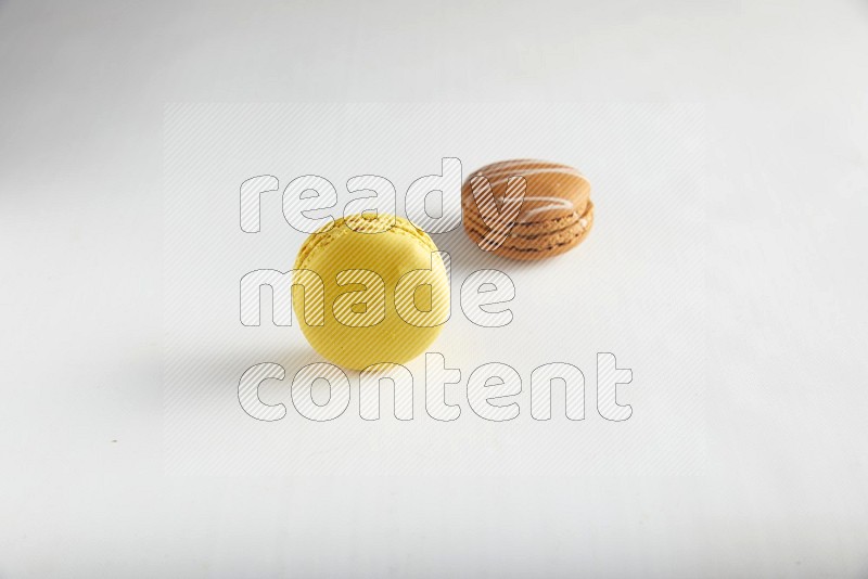 45º Shot of of two assorted Brown Irish Cream, and Yellow Lemon macarons on white background