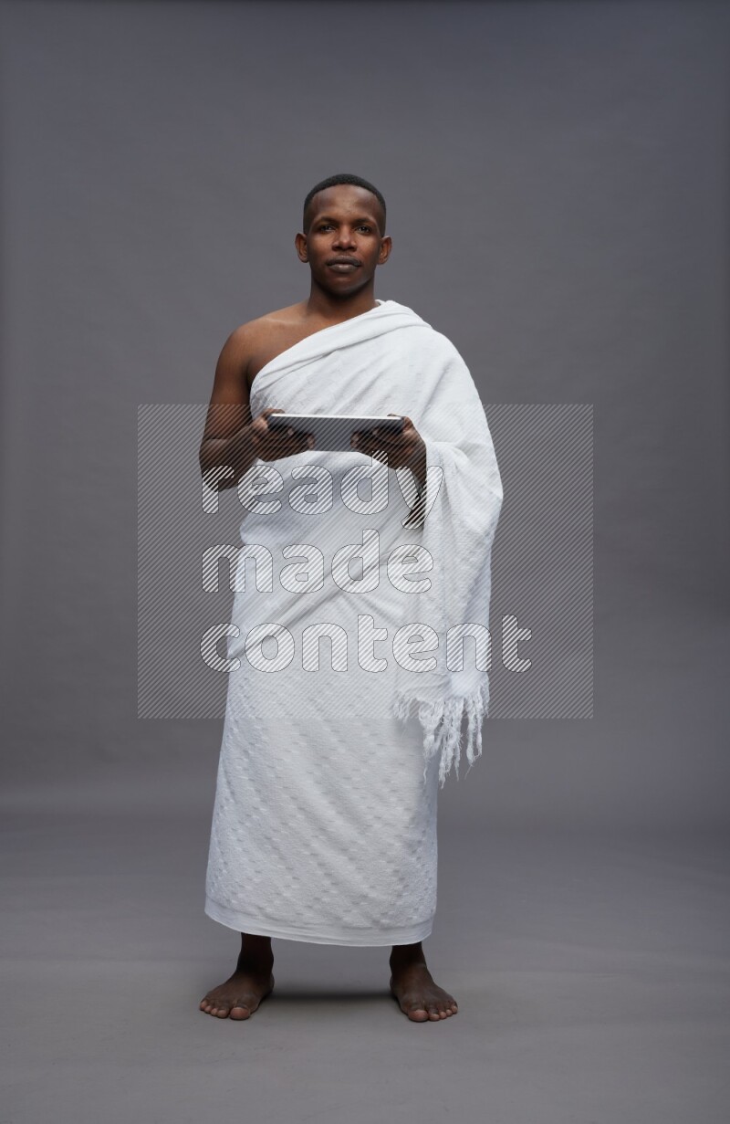 A man wearing Ehram Standing working on tablet on gray background
