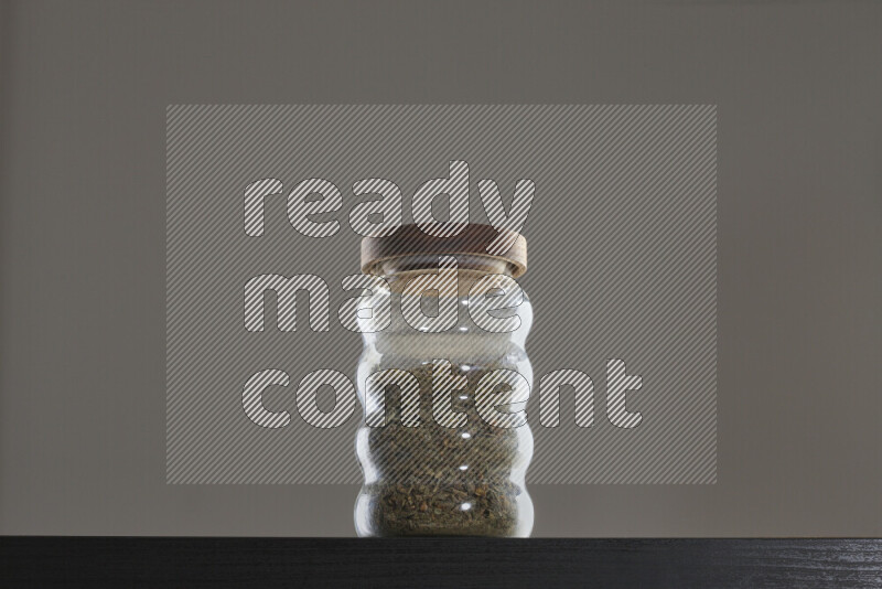 Dried basil in a glass jar on black background