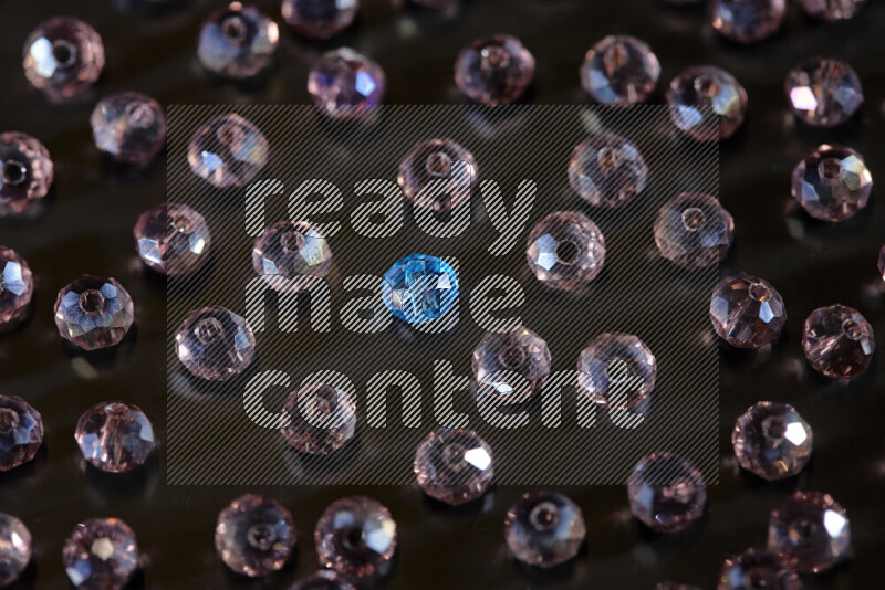 Rose and blue transparent crystal beads scattered on a black background