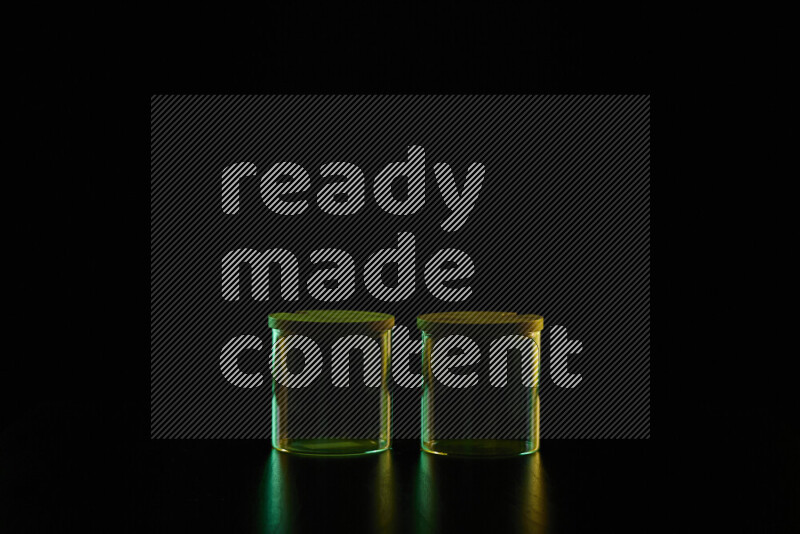 Glassware with rim light in green and yellow against black background