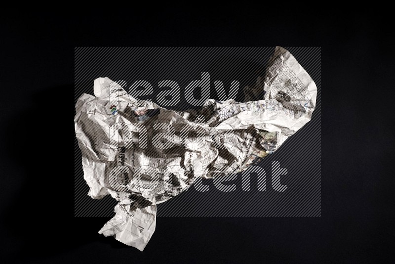 Crumpled newspaper sheet on black background