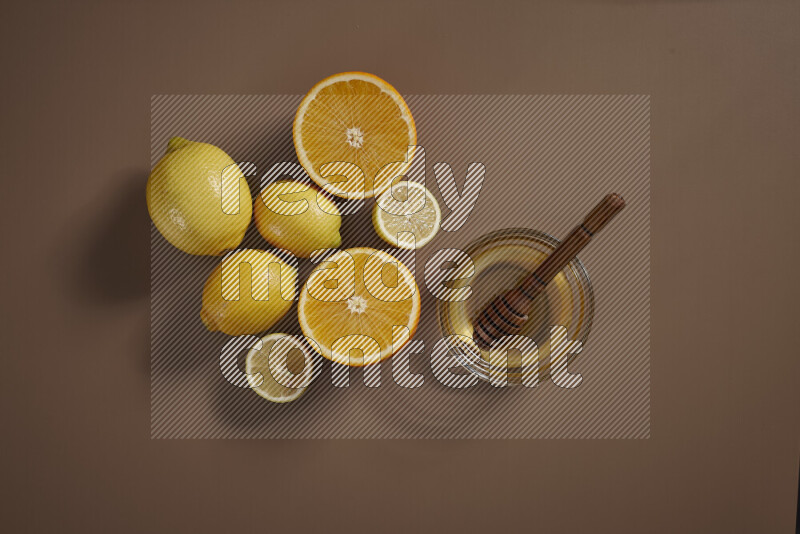 A bowl full of honey with some of citrus fruits such as lemon and orange on a beige background