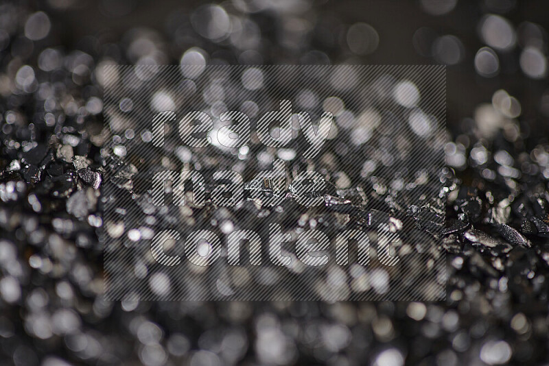 Black shimmering fragments of glass scattered on a black background