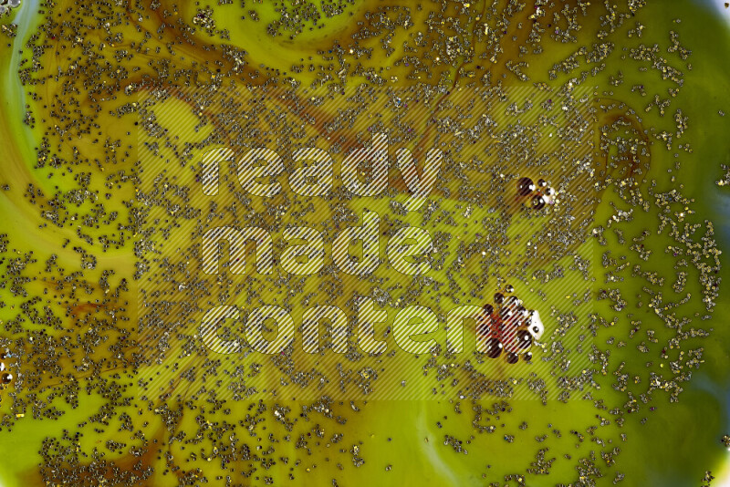 لقطة مقربة لبريق ذهبي متلألئ منتشر على خلفية من اللون الأخضر والأحمر في حركات دائرية