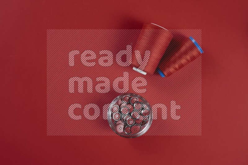 مجموعة من أدوات الخياطة والتفصيل حمراء اللون على خلفية حمراء