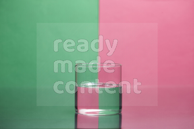 The image features a clear glassware filled with water, set against green and pink background