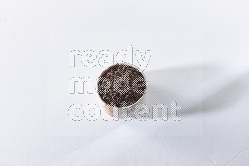 وعاء بيج من السيراميك ممتلئ بحبوب القرنفل علي خلفية بيضاء