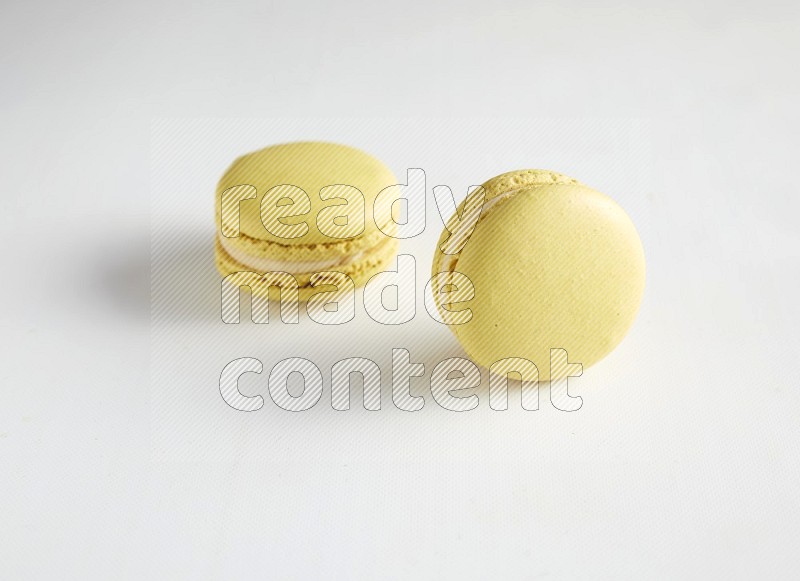 45º Shot of two Yellow Lime macarons on white background