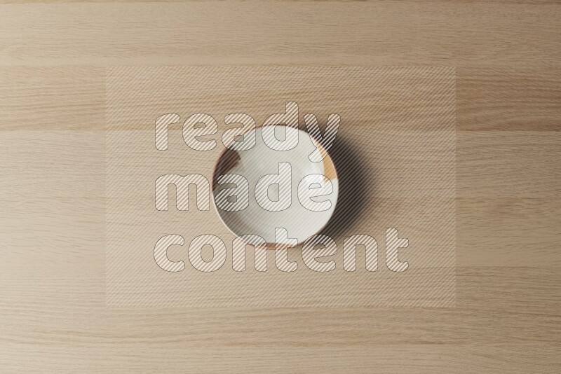 A multicolored pottery plate on light wooden background