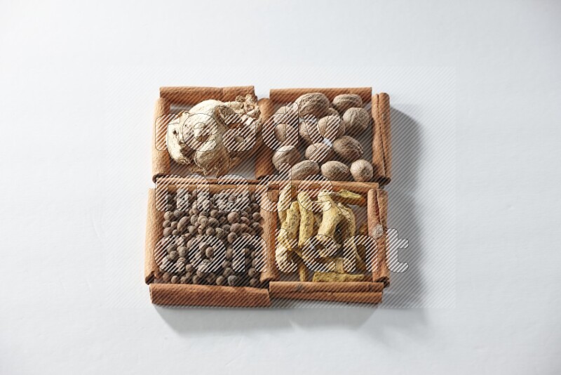 4 squares of cinnamon sticks full of nutmegs, dried ginger, turmeric fingers and allspice on white flooring
