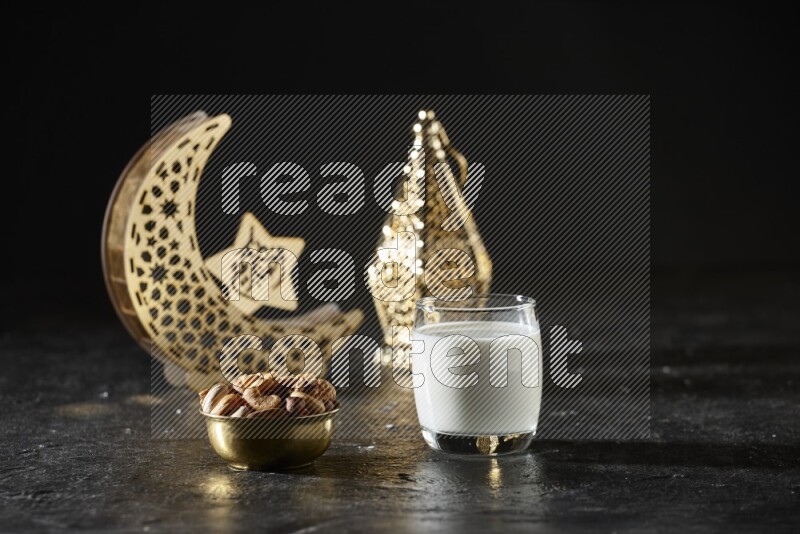 مكسرات في وعاء معدني مع الحليب بجانب فوانيس ذهبية علي خلفية سوداء