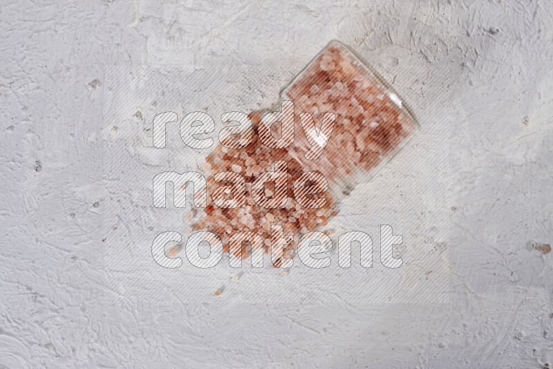 A glass jar full of coarse himalayan salt crystals on white background