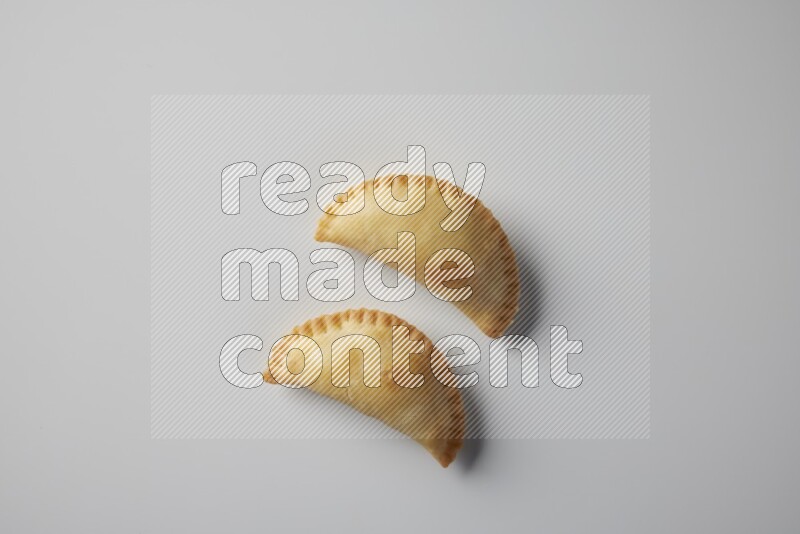 Two fried sambosa from a top angle on a white background