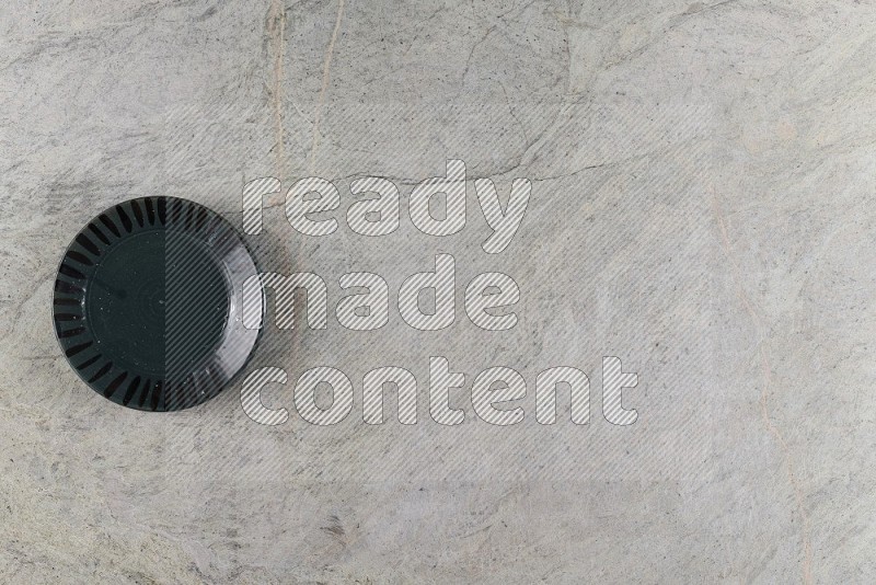 Top View Shot Of A Dark Green Pottery Plate On Grey Marble Flooring
