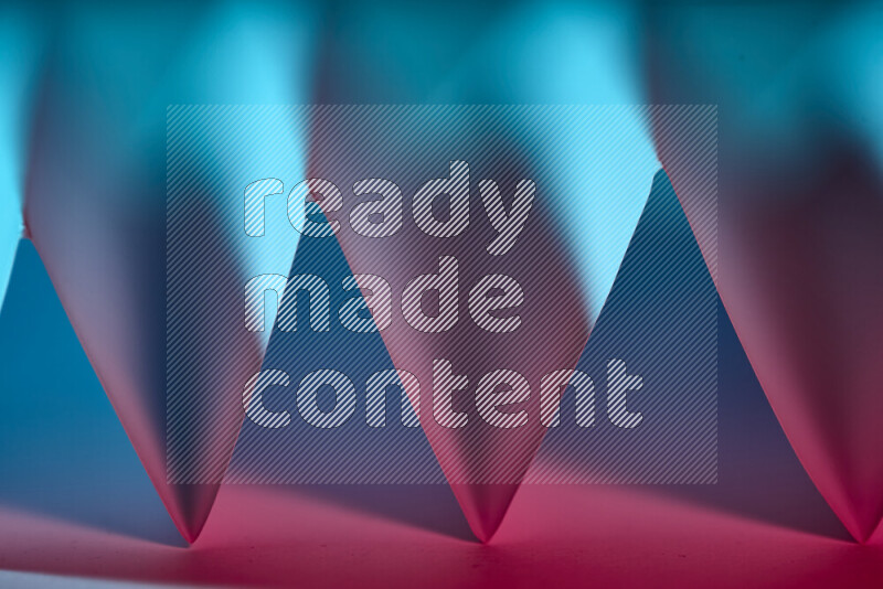 A close-up abstract image showing sharp geometric paper folds in blue and red gradients