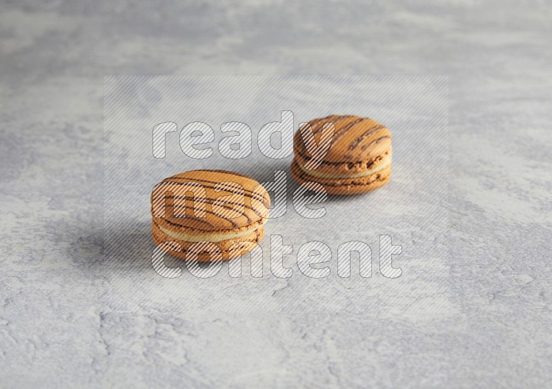 45º Shot of two light brown  Almond Cream macarons  on white  marble background