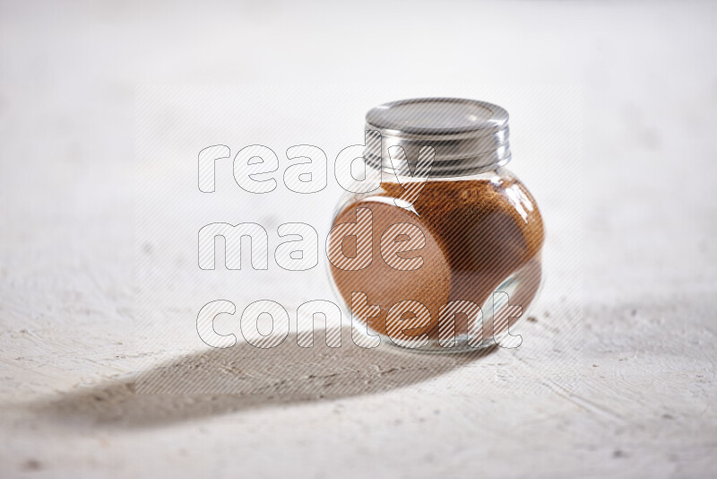 A glass jar full of ground paprika powder on white background