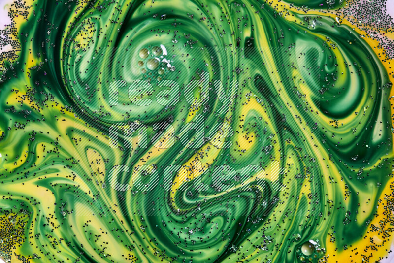 A close-up of sparkling green glitter scattered on swirling yellow and green background