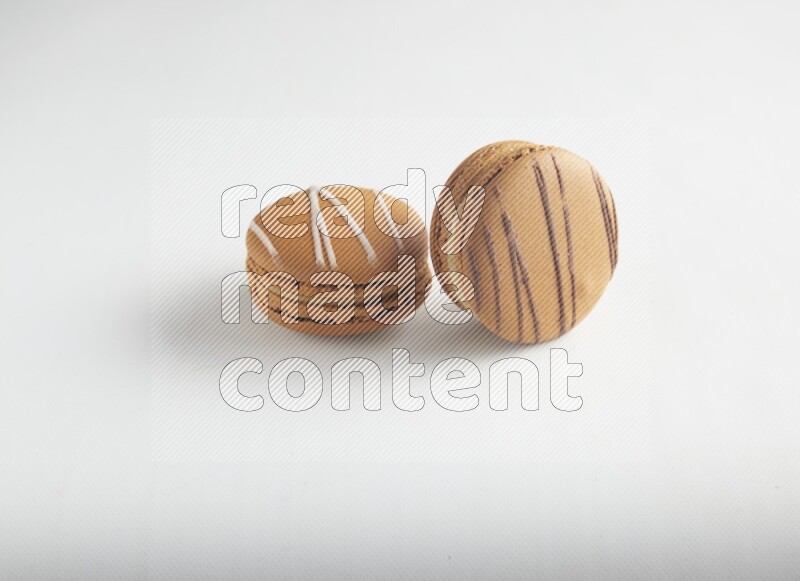 45º Shot of of two assorted Brown Irish Cream, and light brown  Almond Cream macarons on white background