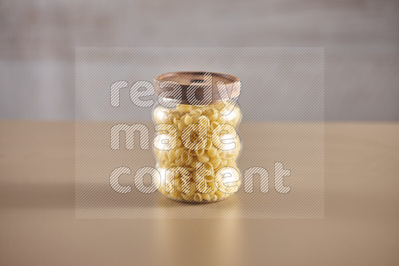 Raw pasta in glass jars on beige background