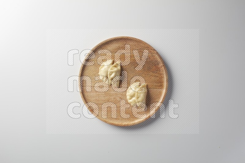Four Sambosas on a wooden round plate on a white background