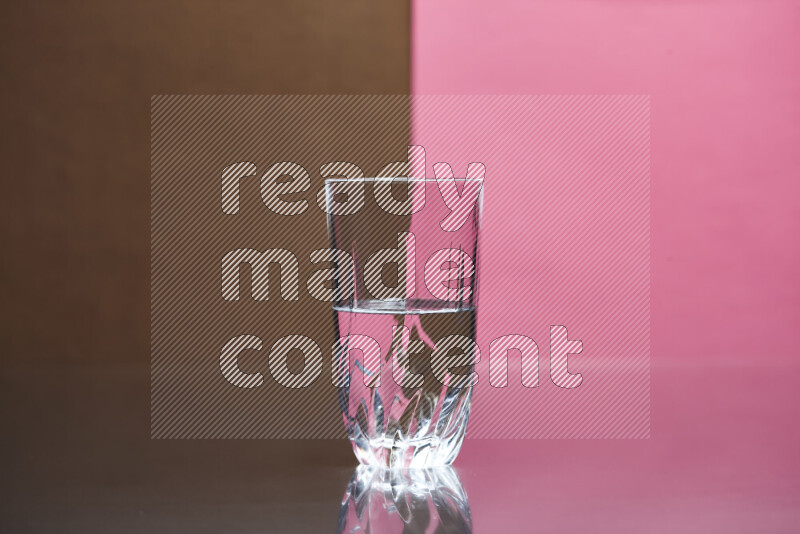 The image features a clear glassware filled with water, set against brown and pink background