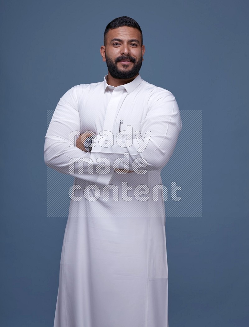 A man Posing in Blue Background wearing a Saudi Thob