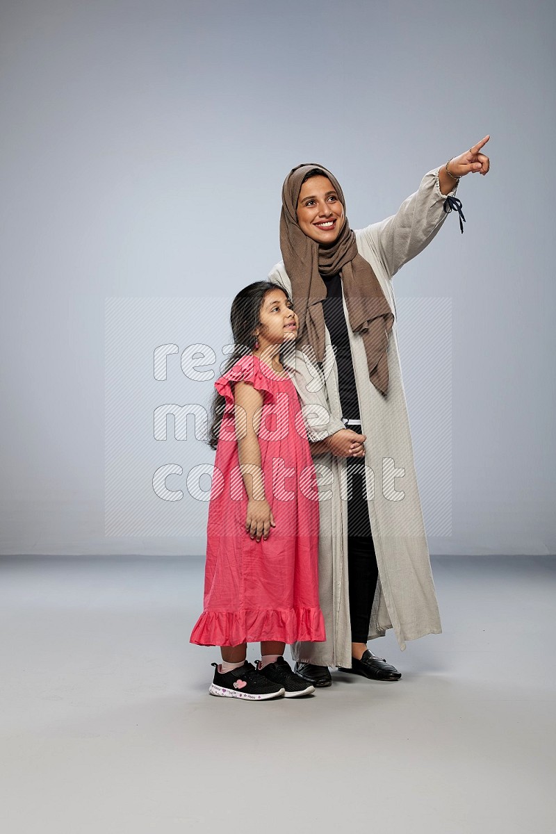 A girl and her mother interacting with the camera on gray background