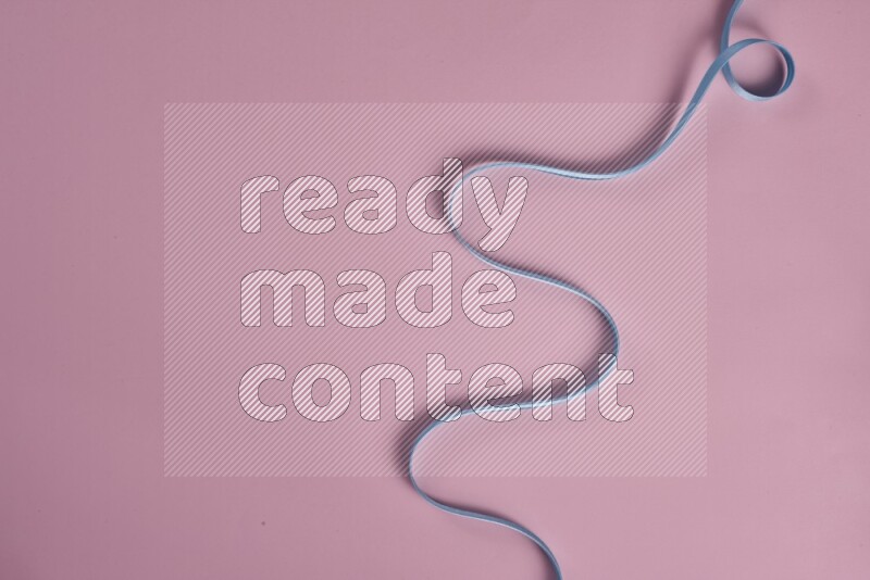 A blue collection of sewing and tailoring tools arranged on a pink background