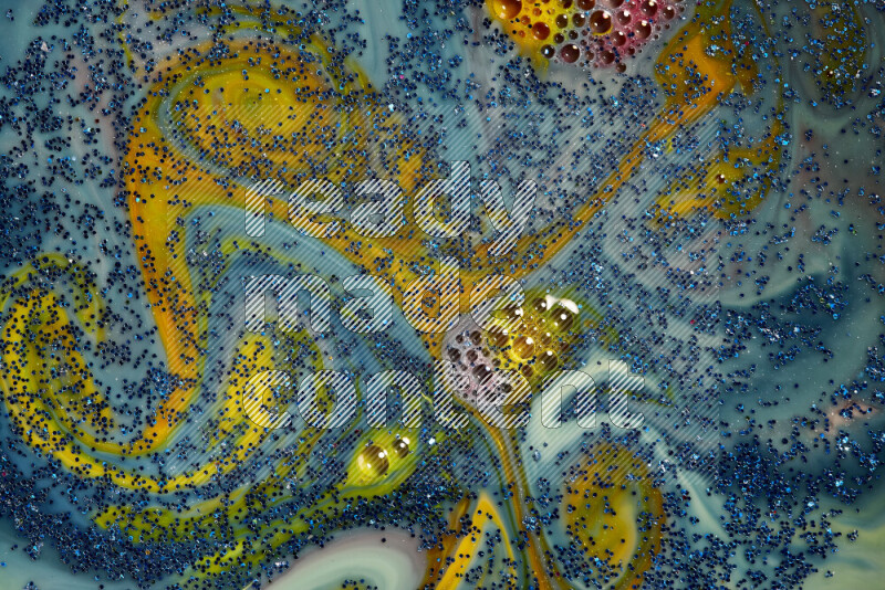 A close-up of sparkling blue glitter scattered on swirling blue and yellow background