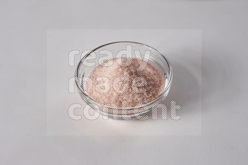 A glass bowl full of fine himalayan salt on white background