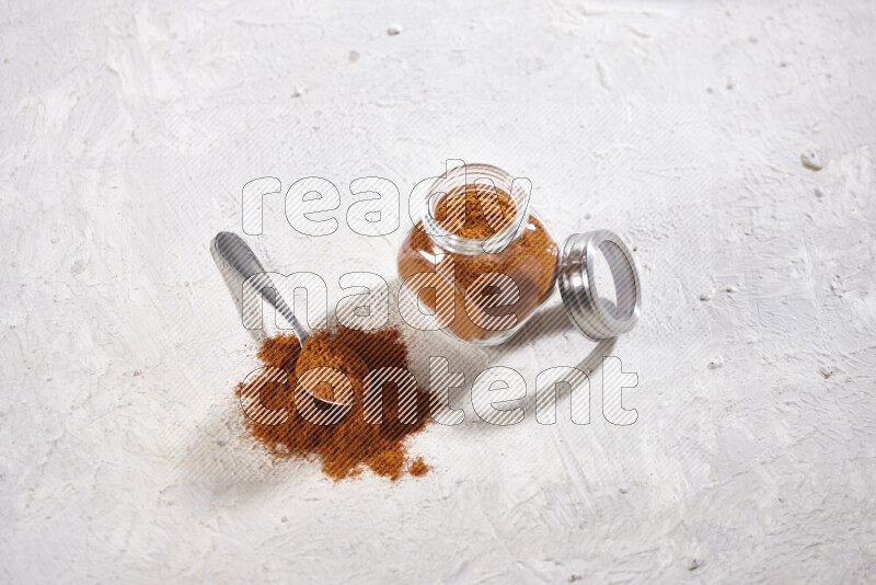 A glass jar full of ground paprika powder on white background