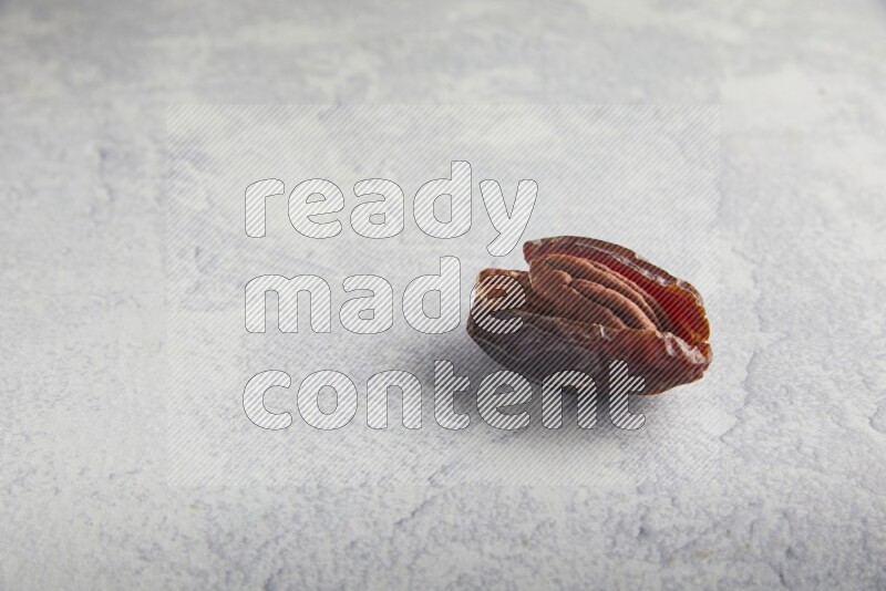 pecan stuffed madjoul date on a light grey background
